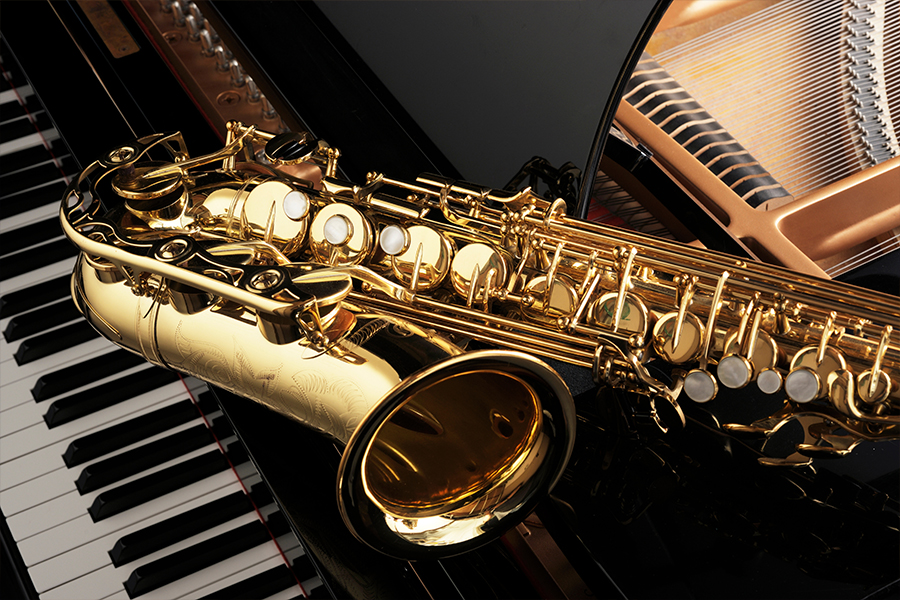 Close-up of a saxophone resting on an open grand piano.
