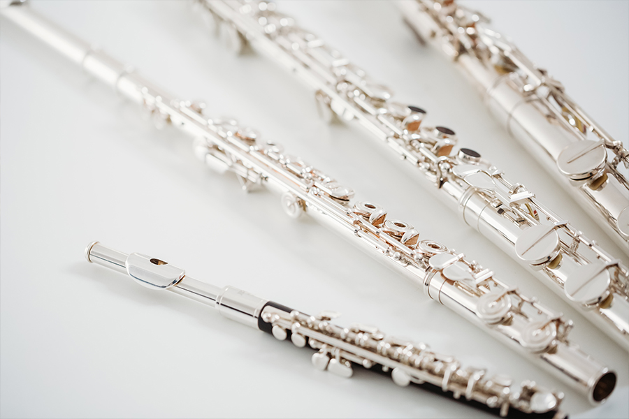Close-up of several silver flutes arranged diagonally on a white surface.